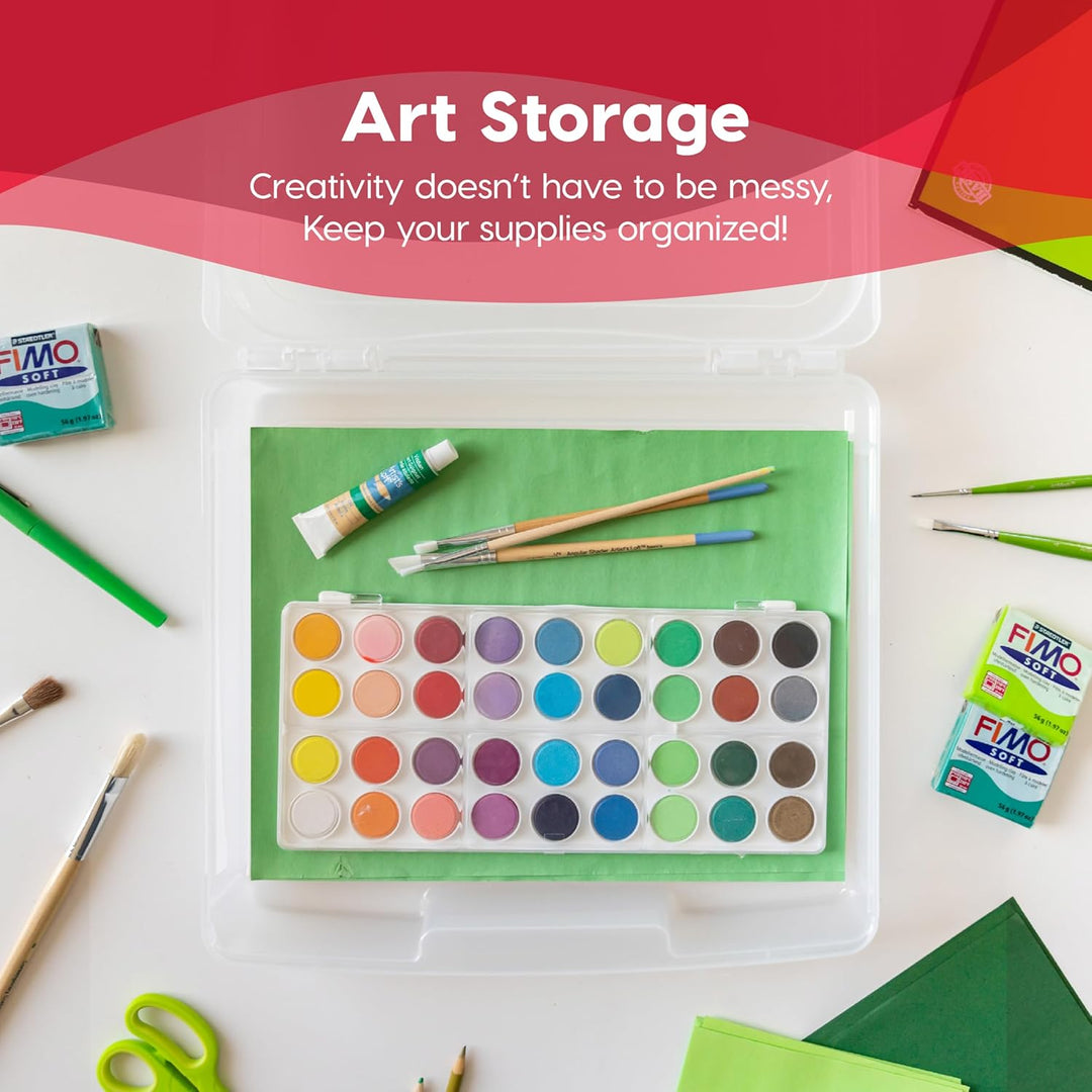 Art storage container with watercolor palette, brushes, and FIMO clay on a red background