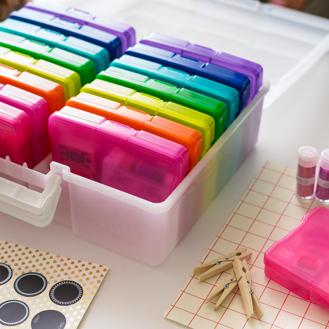 Colorful photo boxes in a white container on a table with stationery items.

